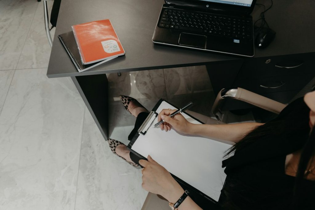 A professional writing notes beside a laptop
